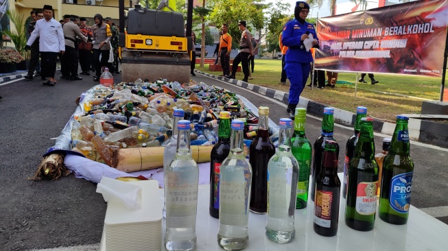 Sejumlah minuman keras (miras) dihancurkan oleh alat berat di halaman Mapolres Gunungkidul, Selasa (22/10/2024). [Kontributor Suarajogja.id/Julianto]